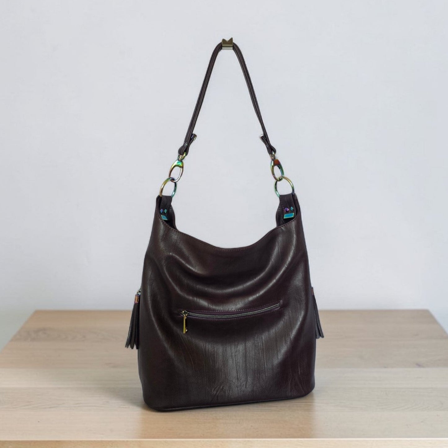A Slouchy multi pockets eggplant color bag with iridescent hardware and decorative zipper tassels