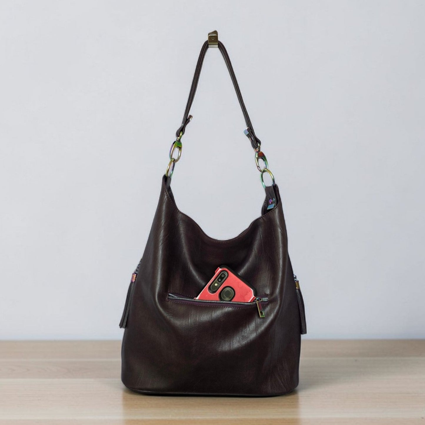 A Slouchy multi pockets eggplant color bag with iridescent hardware and decorative zipper tassels