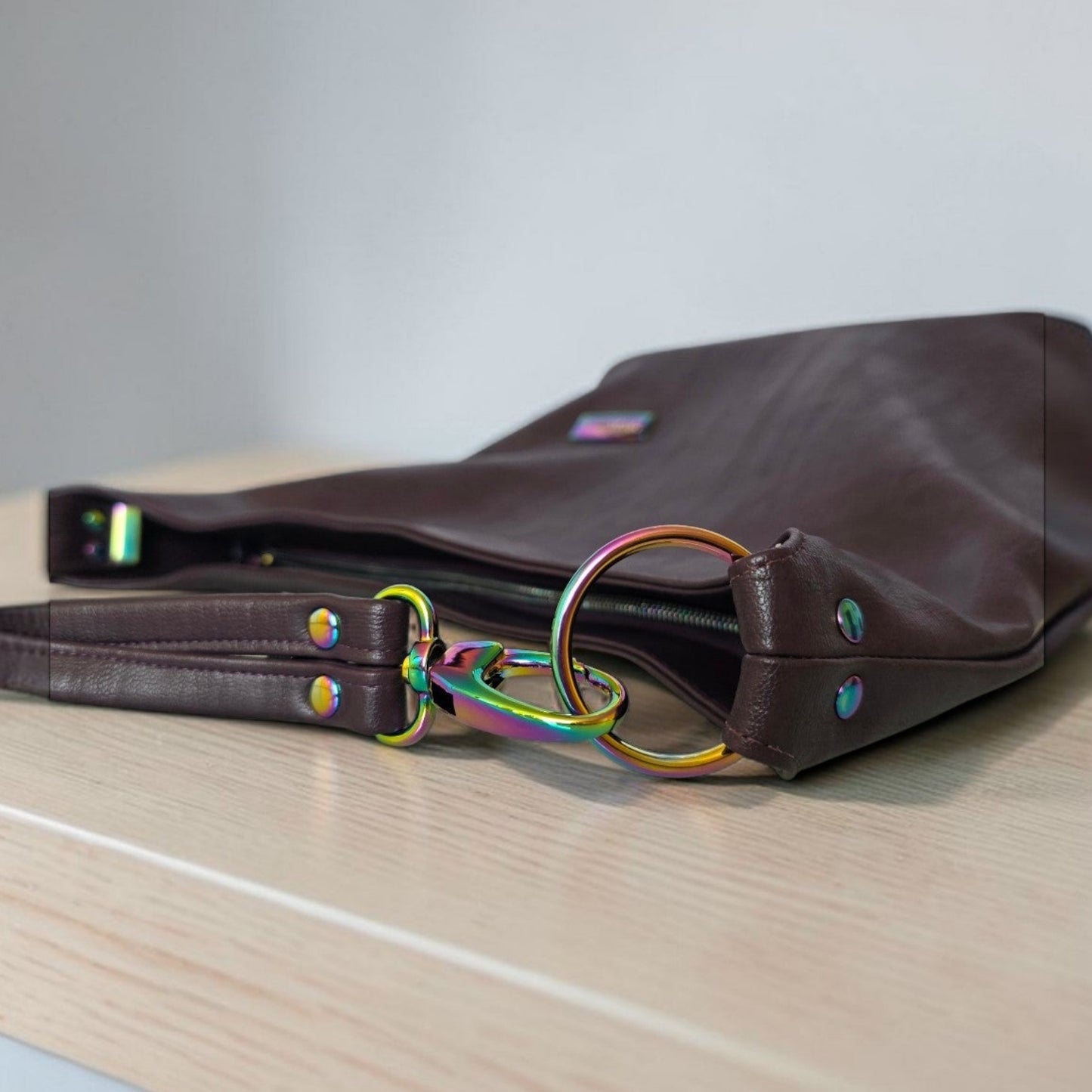 A Slouchy multi pockets eggplant color bag with iridescent hardware and decorative zipper tassels