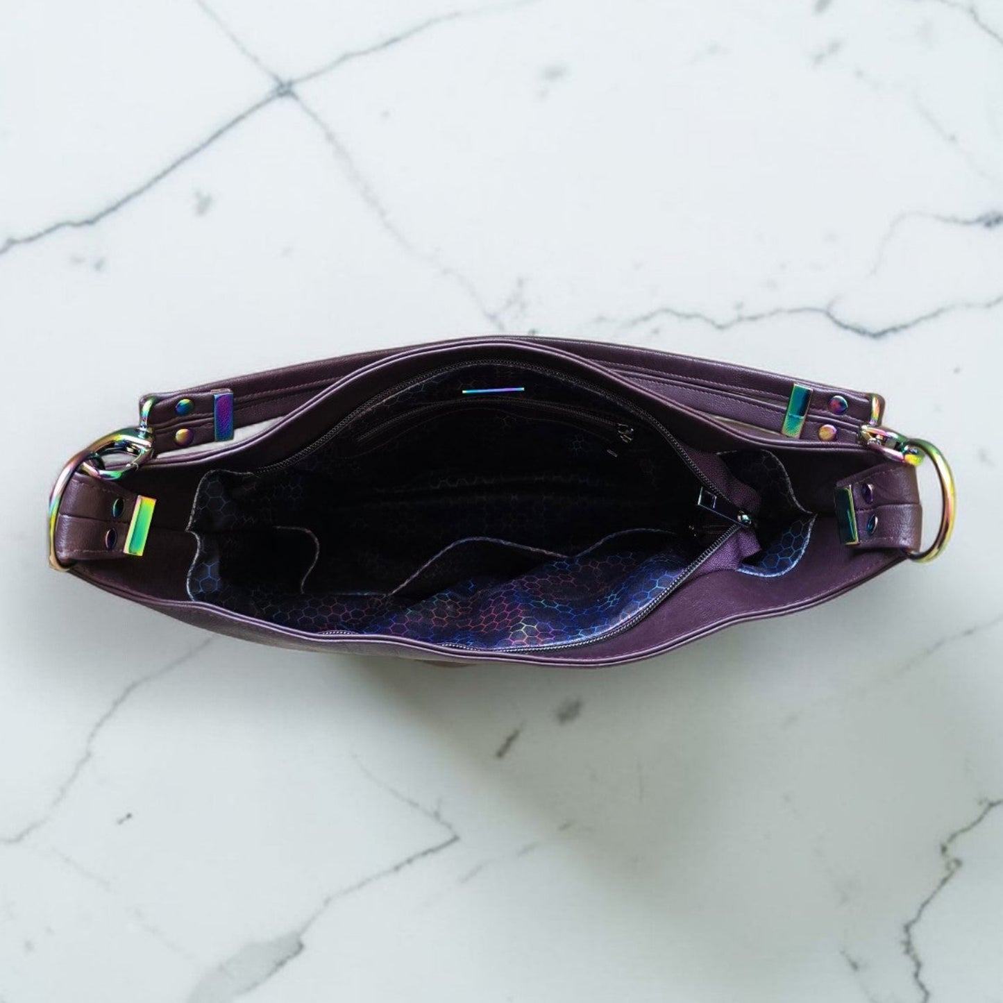 A Slouchy multi pockets eggplant color bag with iridescent hardware and decorative zipper tassels