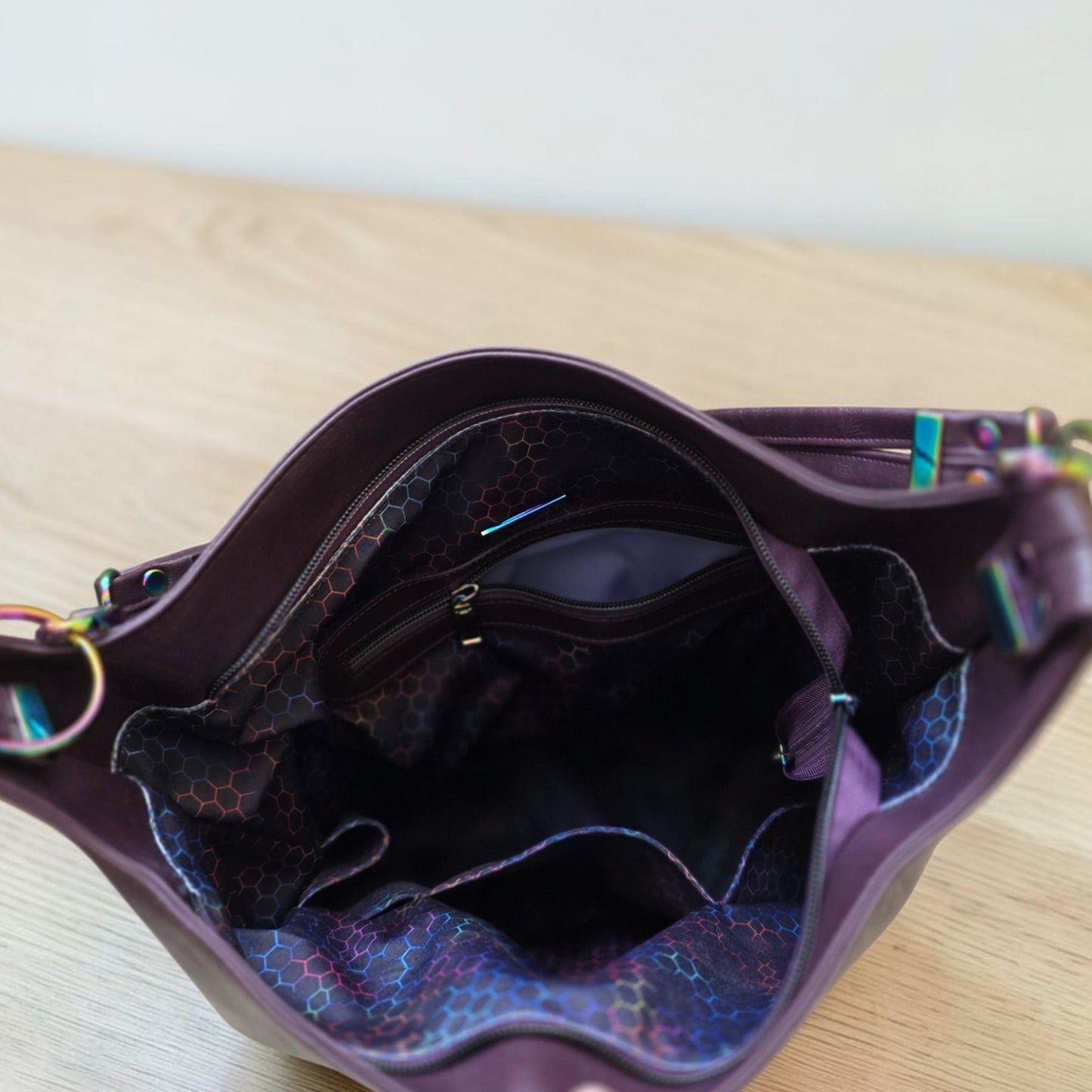 A Slouchy multi pockets eggplant color bag with iridescent hardware and decorative zipper tassels
