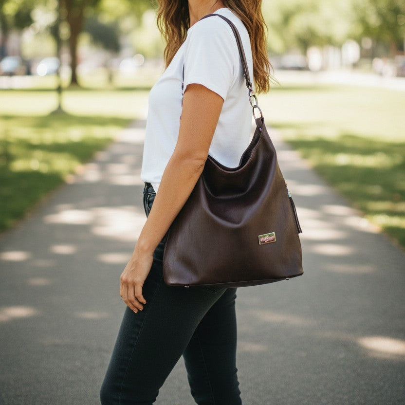 A Slouchy multi pockets eggplant color bag with iridescent hardware and decorative zipper tassels