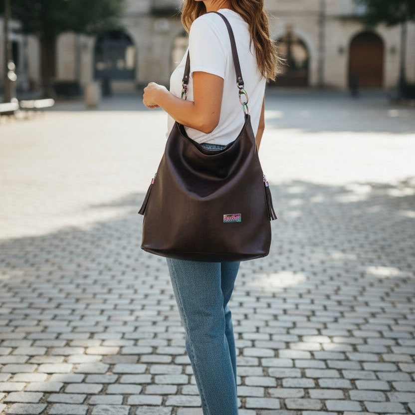 A Slouchy multi pockets eggplant color bag with iridescent hardware and decorative zipper tassels