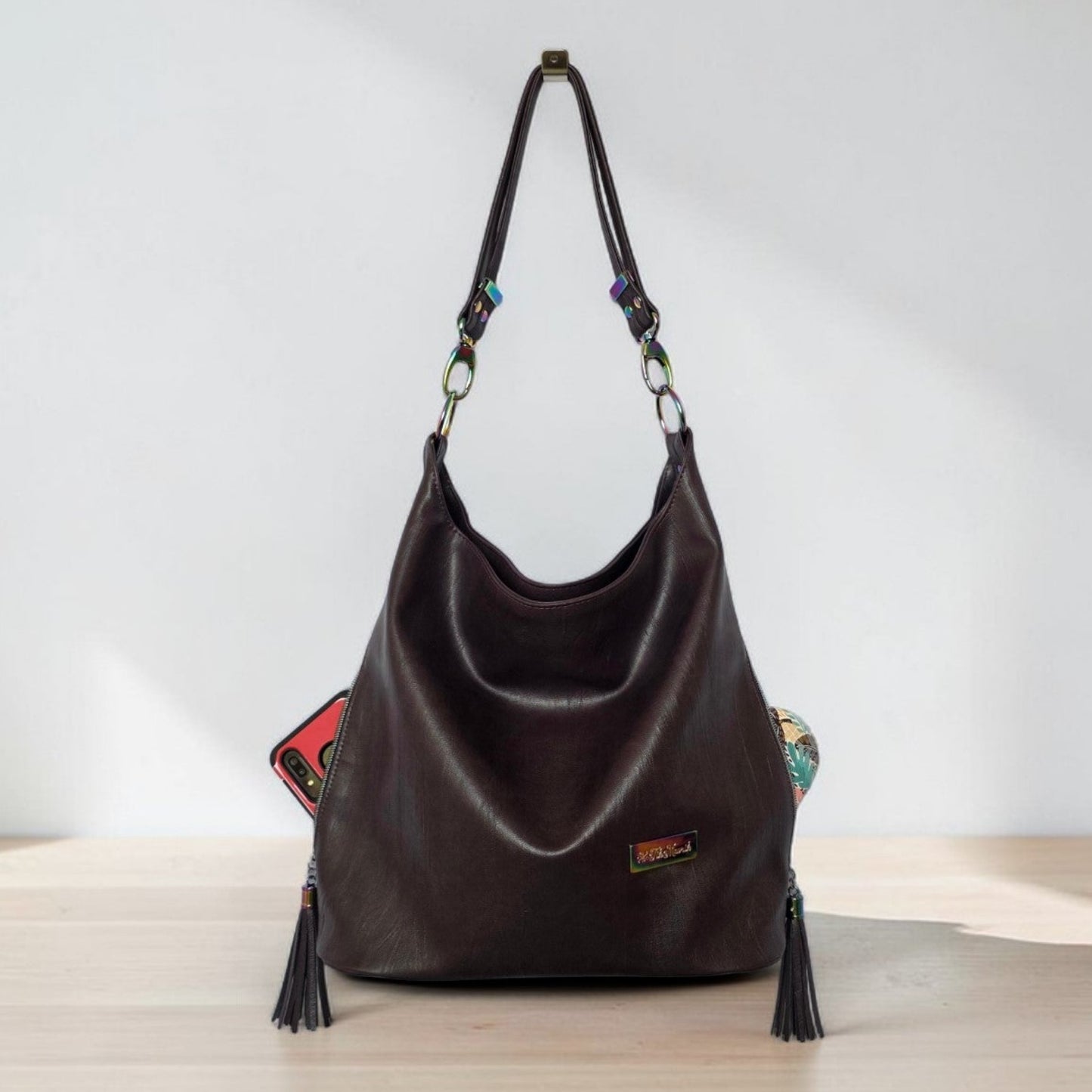 A Slouchy multi pockets eggplant color bag with iridescent hardware and decorative zipper tassels