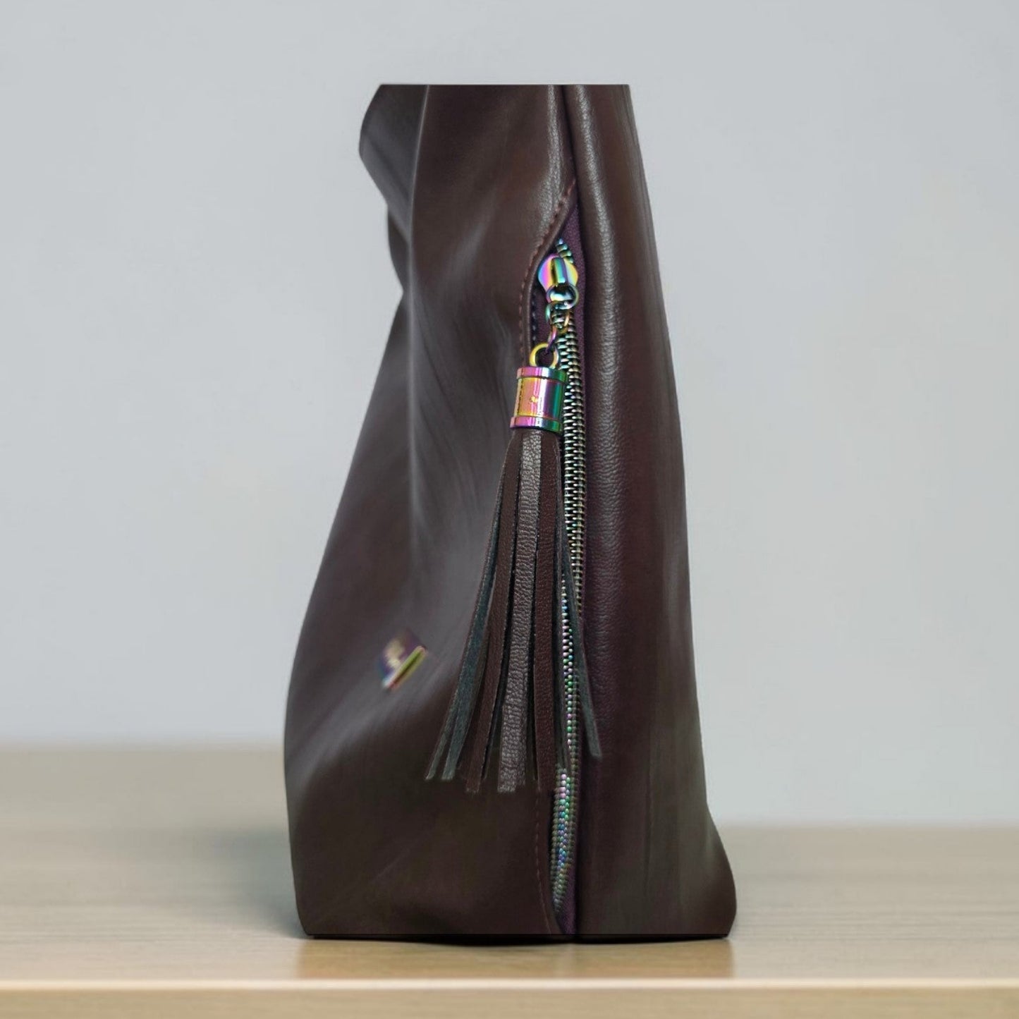 A Slouchy multi pockets eggplant color bag with iridescent hardware and decorative zipper tassels