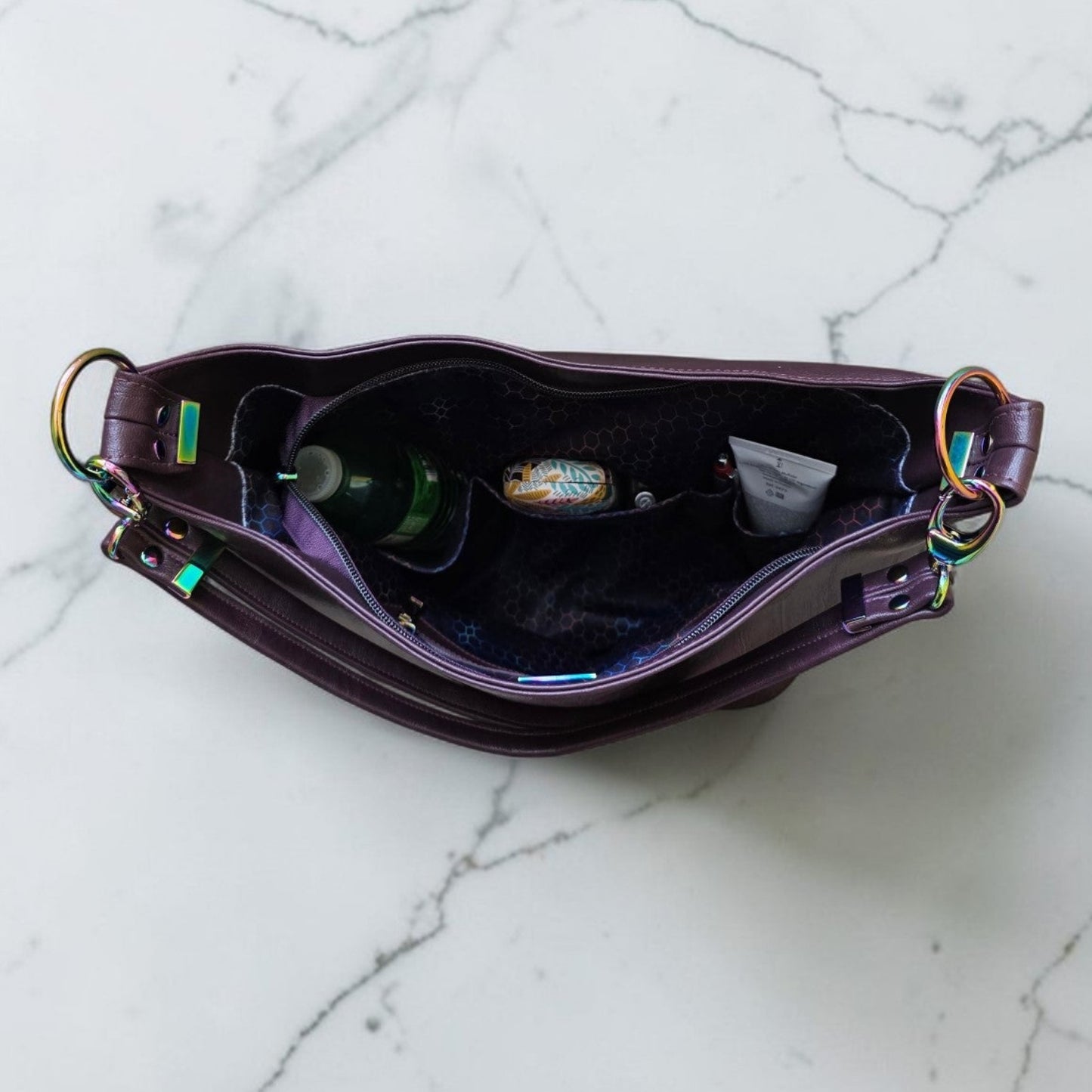 A Slouchy multi pockets eggplant color bag with iridescent hardware and decorative zipper tassels