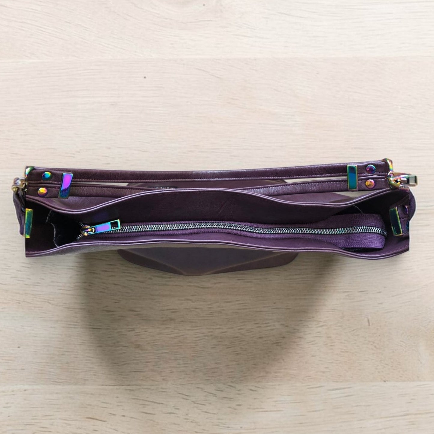 A Slouchy multi pockets eggplant color bag with iridescent hardware and decorative zipper tassels